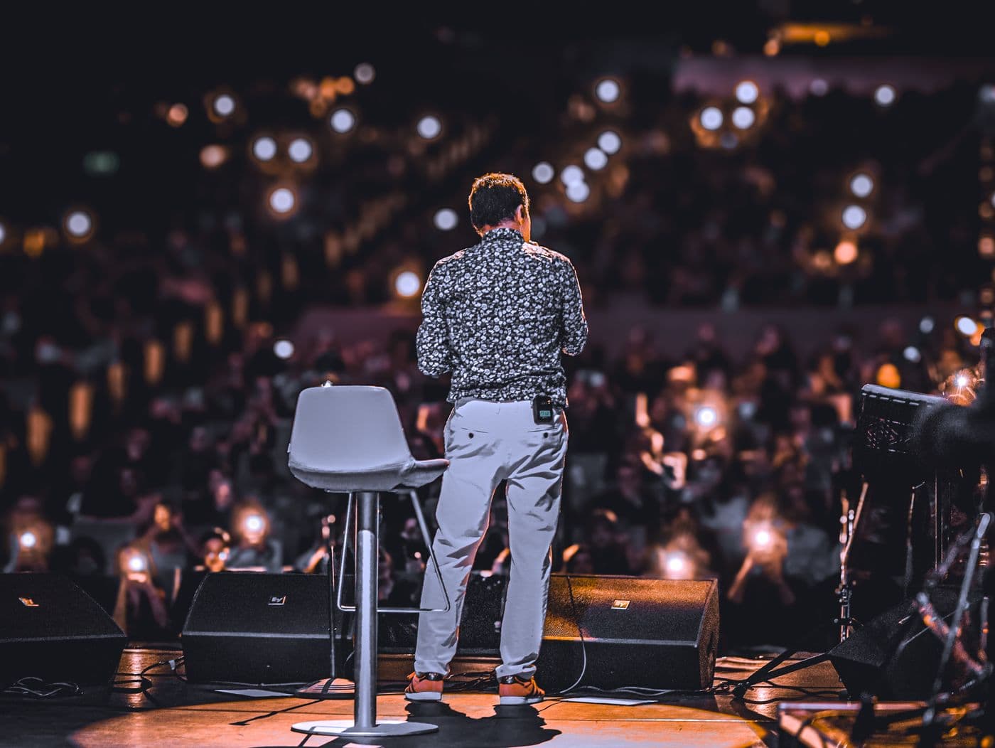A keynote speaker on stage facing a full lit audience
